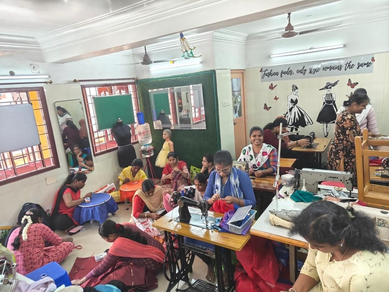 Students practising together at sewing stations inside the Vinu Fashion Academy classroom